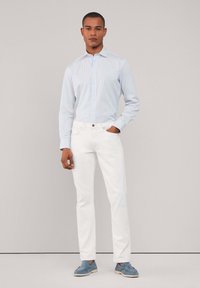 Lichtblauwe gestreepte overhemden met lange mouwen, witte slim-fit jeans en zachte blauwe schoenen. Schoon lijnen, minimalistisch ontwerp.