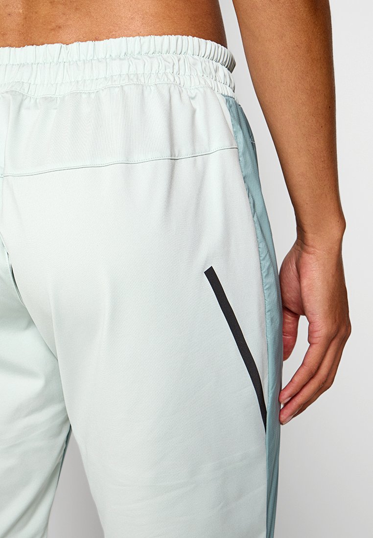 Hellblaue Sporthose mit elastischem Bund und schwarzem Seitenstreifen. Glattes, leichtes Material mit einem subtilen Glanz.