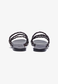 Black flat sandals with two braided straps, open toe design, smooth leather material, minimalist style, and a textured footbed.