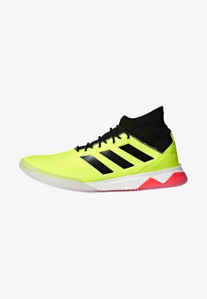 Neon žluté sportovní boty s černým límcem připomínajícím ponožku, černými tkaničkami, třemi černými pruhy na boku a bílou podešví s červeným akcentem poblíž paty.