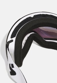 Ochelari de schi cu interior din spumă neagră, carcasă exterioară albă cu un logo și lentile tonificate încadrați în negru, având un design curbat.