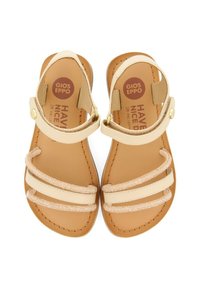 Sandalias beige con tres correas brillantes y cierre en el tobillo, con una plantilla de cuero suave y suela marrón, diseñadas para la comodidad.