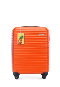 Valise rigide orange avec des côtes horizontales, roues noires et une étiquette en forme d'ananas attachée. Présente un logo sur le devant.