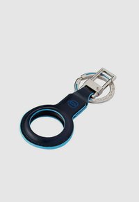 Portachiavi in pelle blu navy con anello circolare e accenti azzurri. Dotato di una clip metallica argentata per l'attacco. Texture liscia, design elegante.
