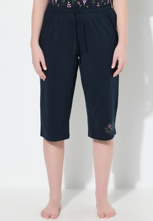Pantalons capri bleu marine en tissu doux avec une taille élastique. Présente une broderie florale en rose et vert sur la jambe gauche.