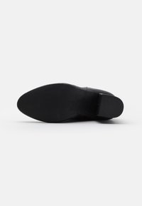 Suela de zapato de cuero negro con una textura suave, forma redondeada y un ligero tacón. Presenta una superficie de tracción con patrón para un mejor agarre.
