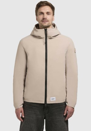 Lys beige polstret jakke med hætte, der har en frontlynlås, sidelommer og et logo badge på venstre ærme.