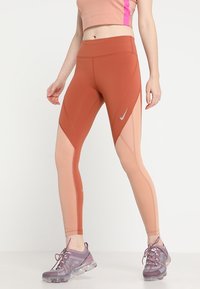 Leggings Nike in un design a blocchi di colore ruggine e pesca, con accenti in rete, tessuto testurizzato e una vita alta per un supporto ottimale.