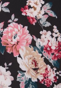Tecido floral com grandes flores em tons de rosa, vermelho e creme sobre um fundo preto, acompanhado de folhas verdes e delicadas flores menores. Textura suave.