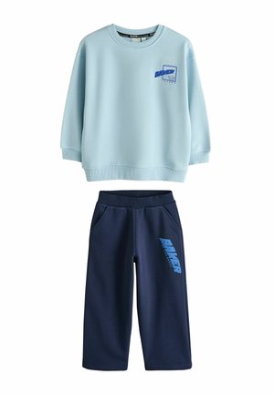 Jasnoniebieska bluza z długim rękawem z logo "Baker" na piersi, w połączeniu z granatowymi spodniami z napisem "Baker" na lewym udzie.