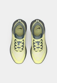 Αθλητικά παπούτσια Nike με επάνω μέρος από ανοιχτό κίτρινο δίχτυ, γκρι λεπτομέρειες και στρογγυλά κορδόνια. Η μεσαία σόλα έχει υφή για καλύτερη πρόσφυση.