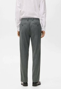 Pantalons tailleur gris avec une finition texturée, taille élastique et deux poches arrière. Portés avec une chemise blanche et des chaussures noires.