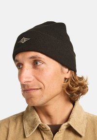 Beanie nera a costine con risvolto, caratterizzata da un design a maglia testurizzata e un piccolo patch con logo sulla parte anteriore.