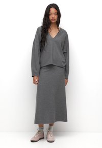 Set di abbigliamento informale grigio composto da una maglia a maniche lunghe con scollo a V e una gonna abbinata fino alla caviglia, realizzati in tessuto morbido e confortevole.