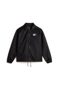 Black nylon jacket with a snap button closure, adjustable drawstring hem, and side pockets. Features a colorful logo patch on the chest.