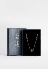 Collana dorata con pendente rotondo blu scuro, collegata da piccoli accenti circolari, esposta in una scatola di gioielli nera testurizzata.