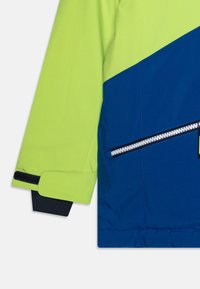 Färgspritt jacka med en livlig limegrön och djupblå design. Tillverkad av mjukt tyg med en dragkedjeficka och kardborrestängningar.