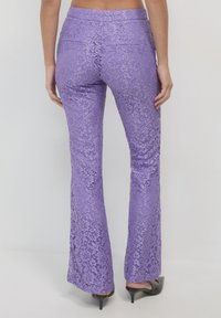 Jeans a campana viola in pizzo con motivo floreale intricato, design aderente e tasche posteriori standard. Presentano una texture morbida e vita media.