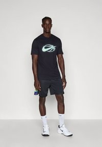 Must sportlik t-särk valge peegeldava logoga, millele on lisatud mustad lühikesed püksid. Kandmiseks valged tossud ja valged sokid.