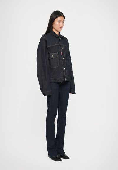 Veste en denim foncé avec une fermeture à boutons, deux poches poitrine et un col, associée à un pantalon en jean foncé évasé et des chaussures noires pointues.