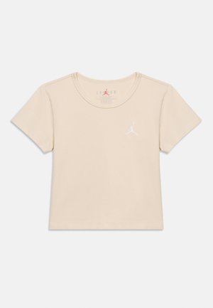 T-shirt court à manches courtes beige avec logo Jumpman blanc sur la poitrine gauche et col rond.
