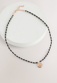 Black bead necklace with rose gold accents and a round pendant. Features a clasp and adjustable chain for length variation.