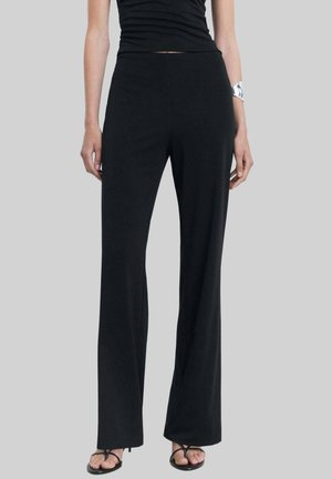 Black wide-leg pants made from soft fabric, featuring a comfortable waistband and a smooth texture. Paired with black sandals.