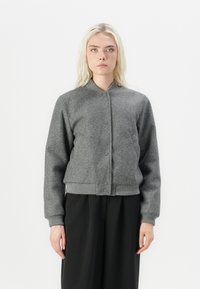 Giacca bomber grigia corta realizzata in tessuto morbido, con chiusura a bottoni, polsini a coste e un design minimalista.