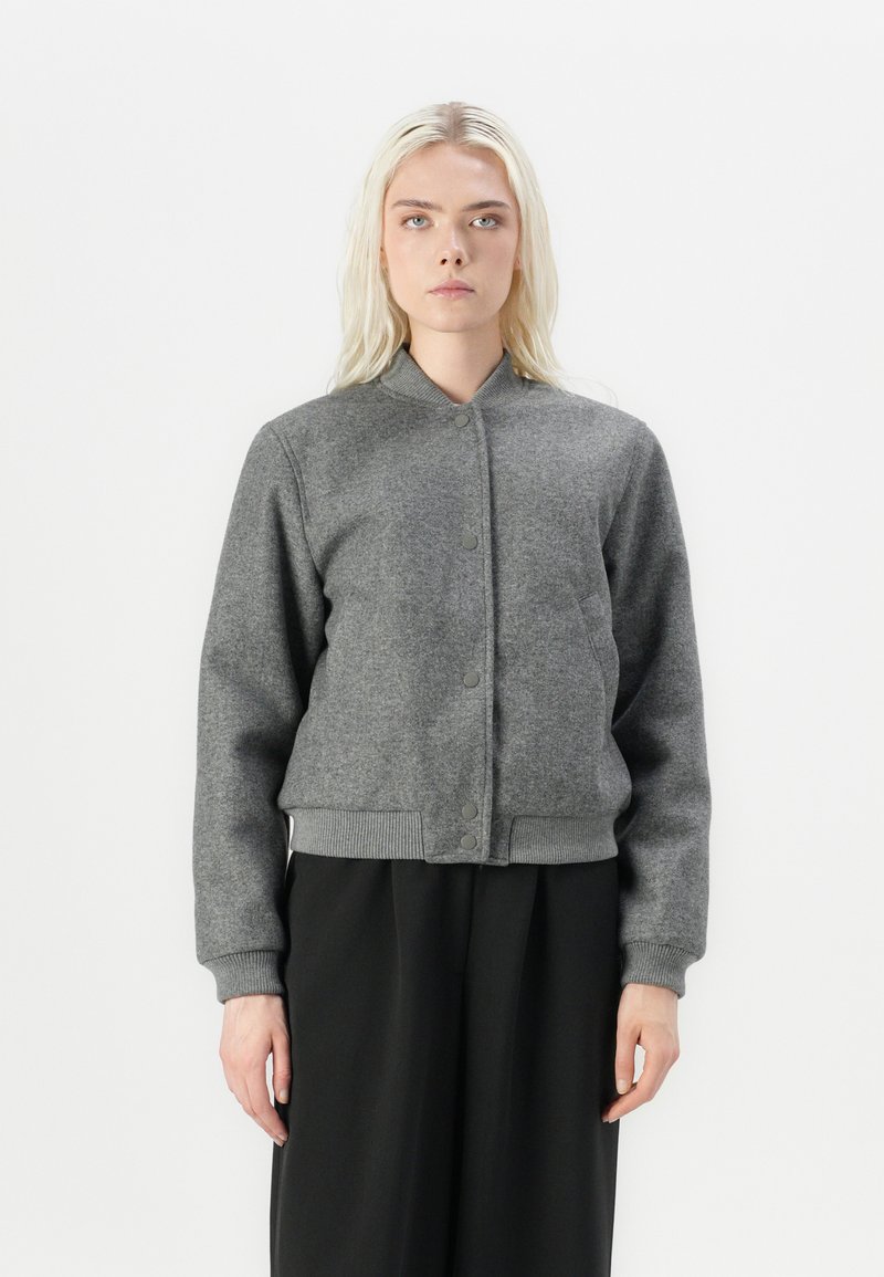 Giacca bomber grigia corta realizzata in tessuto morbido, con chiusura a bottoni, polsini a coste e un design minimalista.