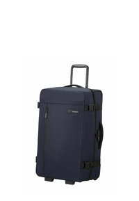 Valise à roulettes bleu marine avec un extérieur en tissu texturé, une poignée noire robuste, plusieurs sangles et une poche zippée à l'avant.