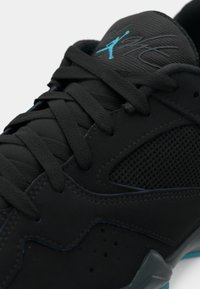 Sneaker sportivo nero con lacci spessi neri, dettagli in rete e logo Jumpman blu sulla linguetta.