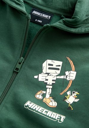 Zielona bluza z kapturem z grafiką postaci z Minecraft, przedstawiającą kanciastą sylwetkę trzymającą łuk i małego białego ptaka; posiada zamek błyskawiczny i metkę.