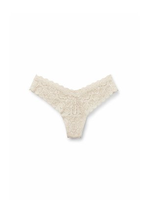 Lace thong in light beige with floral pattern, scalloped edges, and a delicate texture. Features a V-shaped back for minimal coverage.