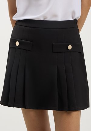 Schwarzer plissierter Rock mit zwei vorderen Taschen und runden goldenen Knöpfen, aus glattem Stoff für einen strukturierten Look.