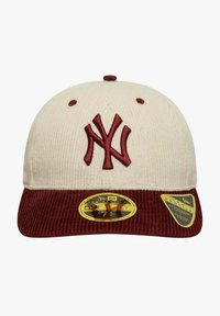 Cappellino New Era con parte superiore in velluto a coste crema e visiera bordeaux, con logo ricamato e adesivo dorato della taglia sulla visiera.