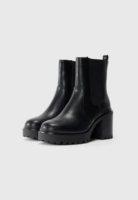 Sorte skinn ankle boots med chunky hæler og elastiske sidepaneler på en hvit bakgrunn.