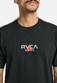 Černé bavlněné tričko s bílým a červeným logem RVCA a čínskými znaky. Jednoduchý design s klasickým kulatým výstřihem, krátkými rukávy a standardním střihem.