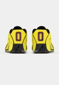Κίτρινα αθλητικά παπούτσια με μαύρες λεπτομέρειες, κατασκευασμένα από διχτυωτό υλικό και με ελαστικές σόλες. Διαθέτουν ένα τολμηρό σχέδιο με τον αριθμό "0" στη φτέρνα.