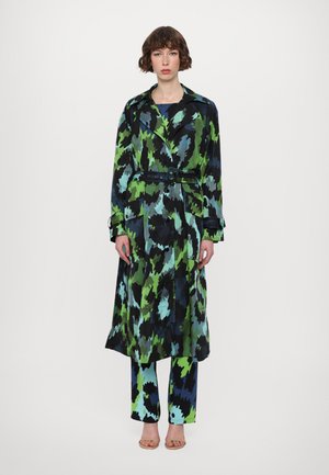 Langer, gemusterter Trenchcoat in Schwarz, Grün und Blau, an der Taille mit einem Gürtel gerafft. Kombiniert mit passenden Hosen in Blau und Grün mit Muster.