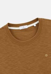 T-shirt à col rond marron en tissu texturé, avec un col côtelé et un petit écusson logo à l'avant.