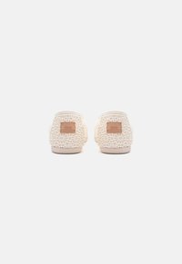 White crochet shoes with a patterned texture, featuring a beige rubber sole and small brown branding patch on the heel.