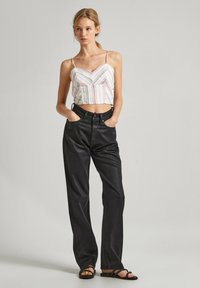 Top corto con strisce rosa e bianche, abbinato a pantaloni ampi neri. Il look presenta spalline sottili e una vestibilità casual. Sandali neri completano l'outfit.