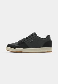Black low-top sneaker with beige sole, lace-up front, perforated side panel, and "Globe" branding on side and heel.