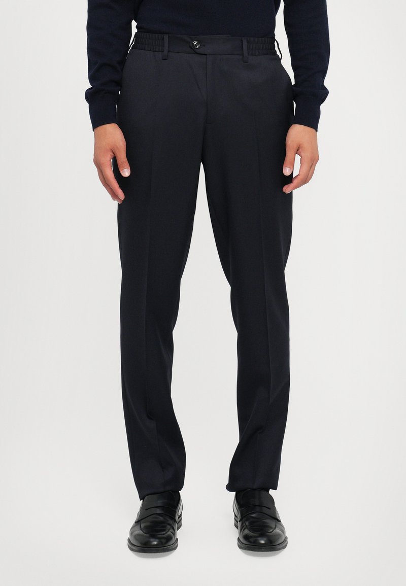 Navy dress trousers with a smooth texture, featuring a fitted waistband, flat front, and sharp creases. Worn with black dress shoes.