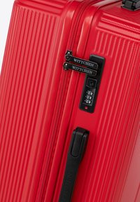 Valigia in policarbonato rosso con texture a righe, doppie cerniere nere, lucchetto a combinazione e marchio WITTCHEN sulle linguette delle cerniere.