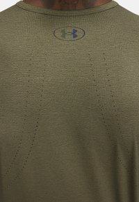 Maglietta sportiva verde oliva con tessuto strutturato, caratterizzata da scollo rotondo, logo stampato blu e dettagli traforati sulla schiena.