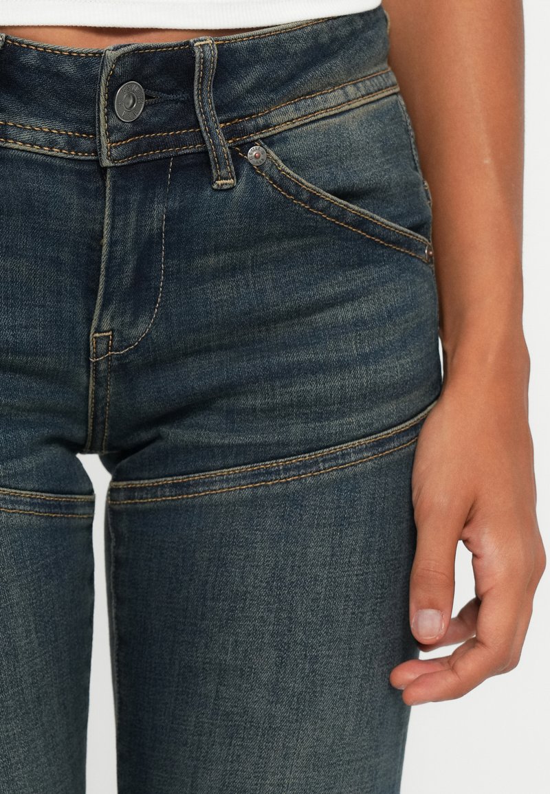 Denim jeans in een donkerblauwe wassing met subtiele vervaging, voorzien van contrasterende stiksels, een knoopsluiting aan de voorkant en zijzakken.