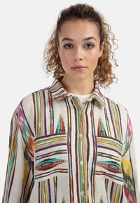 Camicia multicolore con bottoni, caratterizzata da un motivo a righe, vestibilità oversize, due tasche sul petto e un tessuto leggermente testurizzato.