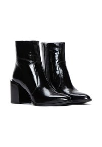 Bottines en cuir verni noir avec des orteils pointus, des talons carrés et une fermeture éclair sur le côté. Texture lisse avec une finition brillante.