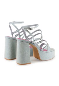 Sandalias de plataforma de denim azul claro con tacones gruesos, múltiples correas en cruz y hebillas plateadas. Plantillas rosas visibles.
